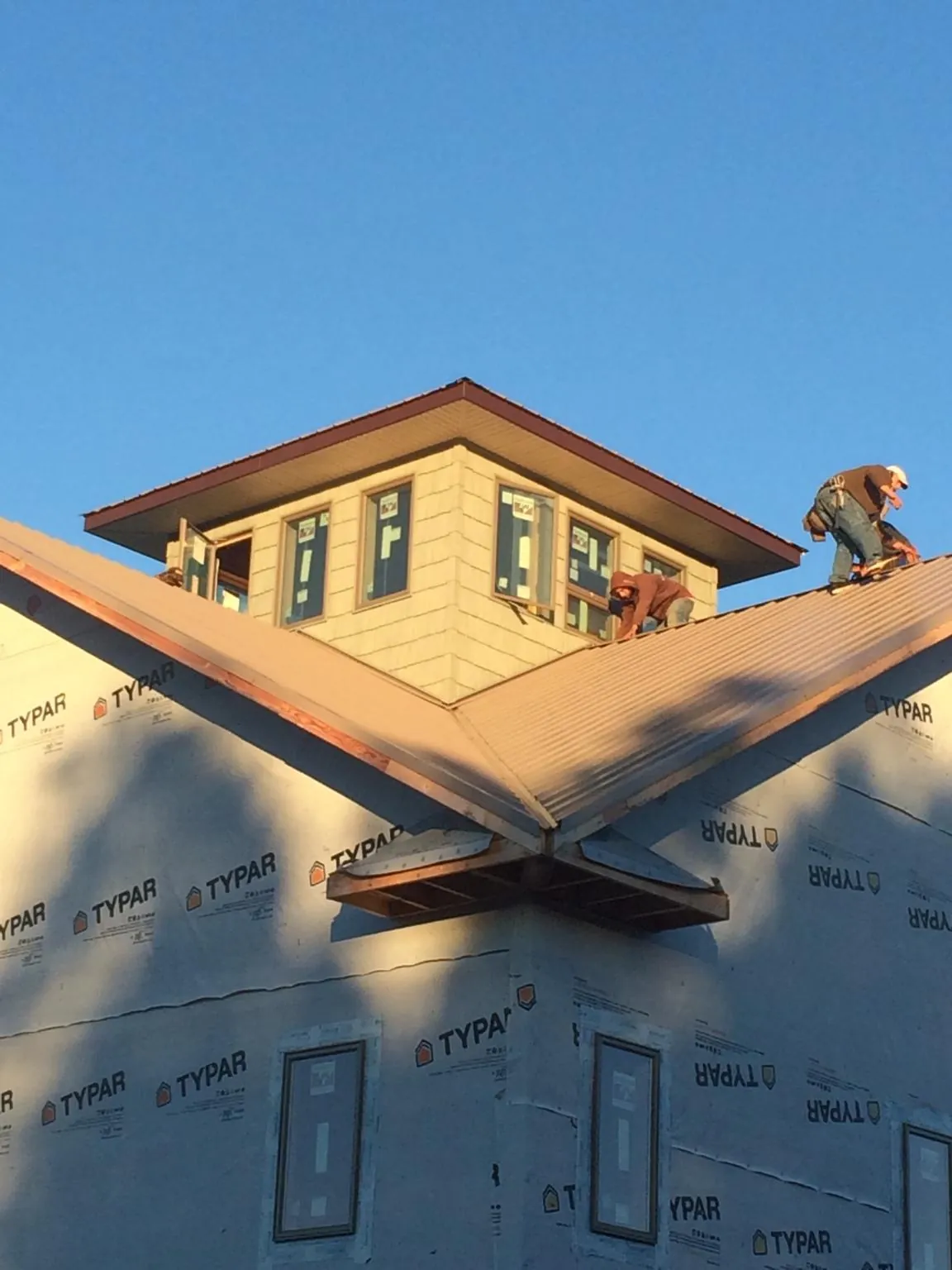 Roofers working around a rooftop cupola on a new metal roof at sunset — Roof Waterproofing in Tarrytown by Roofing Brothers